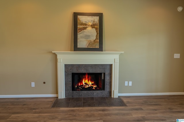 interior details with a tiled fireplace, baseboards, and wood finished floors