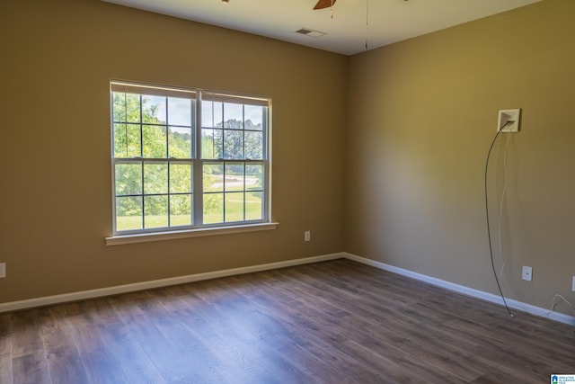 empty room with baseboards, ceiling fan, dark wood finished floors, and visible vents