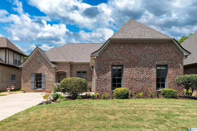 view of front of property featuring brick siding, a front yard, and roof with shingles