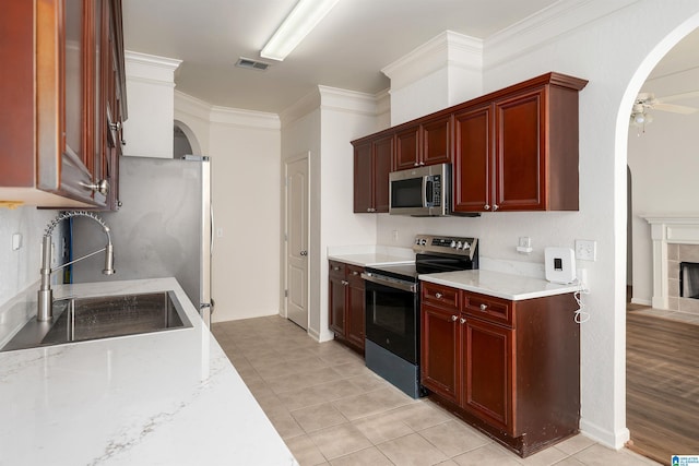 kitchen with a sink, visible vents, stainless steel appliances, and reddish brown cabinets