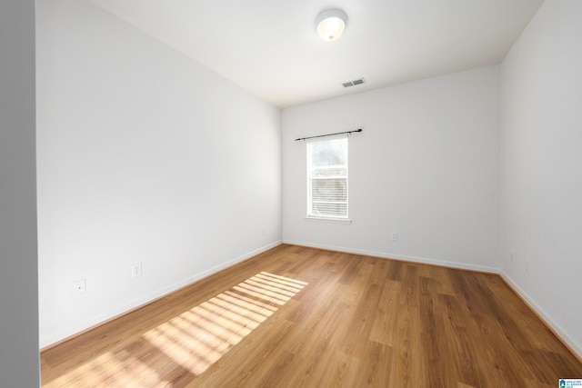 empty room with baseboards, wood finished floors, and visible vents
