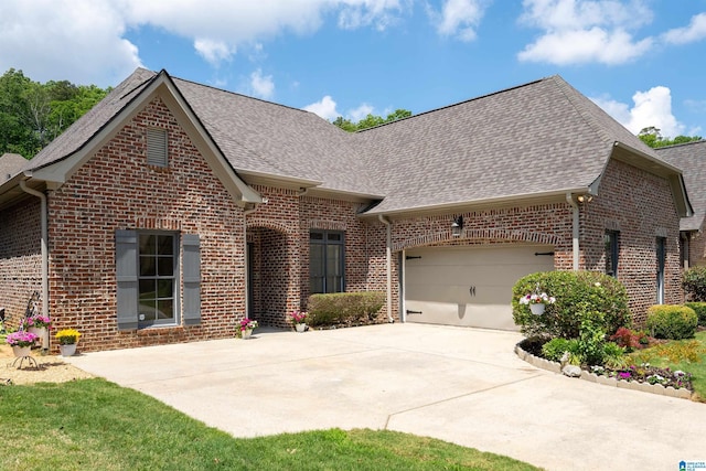 view of front of property featuring roof with shingles, a garage, driveway, and brick siding