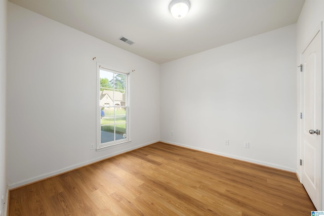 empty room with baseboards, light wood finished floors, and visible vents