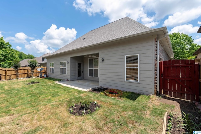 back of house with fence, roof with shingles, a gate, a lawn, and a patio
