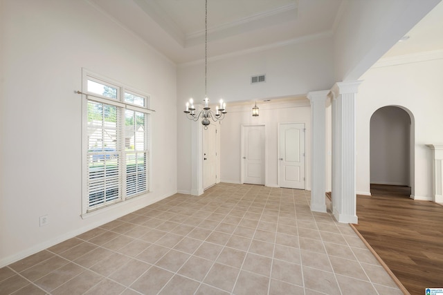 unfurnished dining area with crown molding, light tile patterned flooring, arched walkways, a towering ceiling, and visible vents