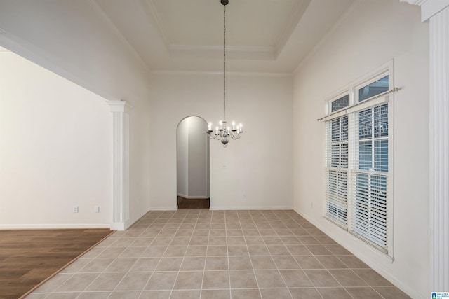 unfurnished dining area featuring crown molding, a high ceiling, a raised ceiling, arched walkways, and a notable chandelier