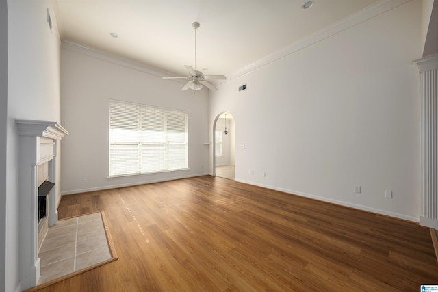 unfurnished living room featuring a ceiling fan, light wood-style flooring, a fireplace, and ornamental molding