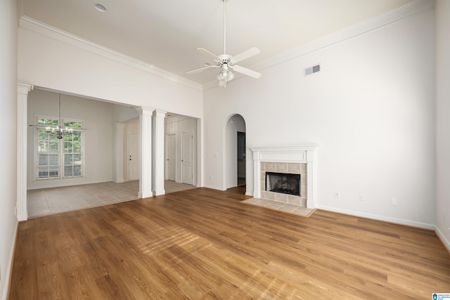 unfurnished living room featuring visible vents, ornamental molding, a fireplace, ceiling fan, and light wood finished floors