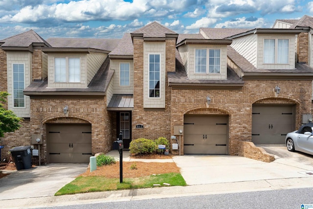 multi unit property featuring a garage, driveway, roof with shingles, and brick siding