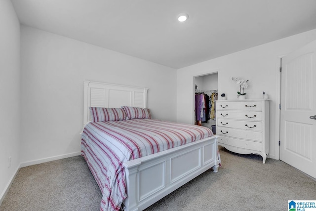 bedroom featuring a walk in closet, baseboards, a closet, light carpet, and recessed lighting