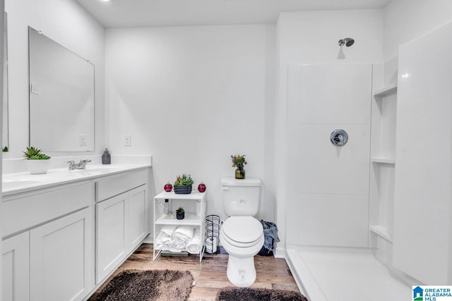 full bath featuring walk in shower, a sink, double vanity, toilet, and wood finished floors