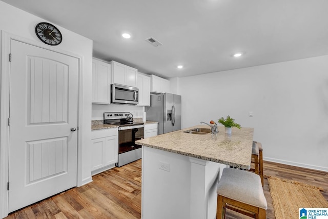 kitchen with visible vents, light wood-style floors, an island with sink, a sink, and stainless steel appliances
