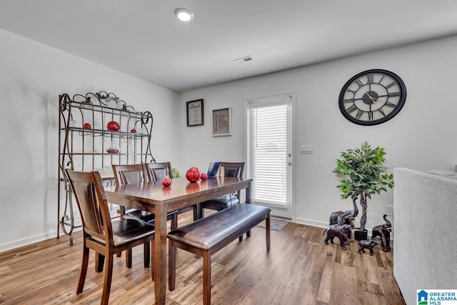 dining area with baseboards, visible vents, and light wood-type flooring