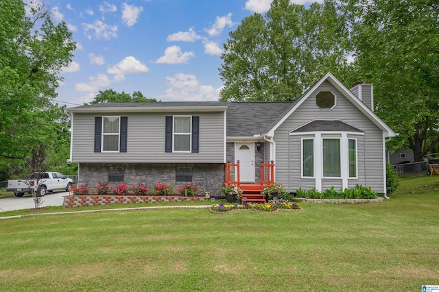 tri-level home with a chimney, a shingled roof, and a front yard