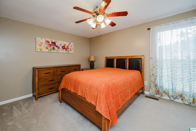 bedroom with baseboards, a ceiling fan, light colored carpet, and visible vents
