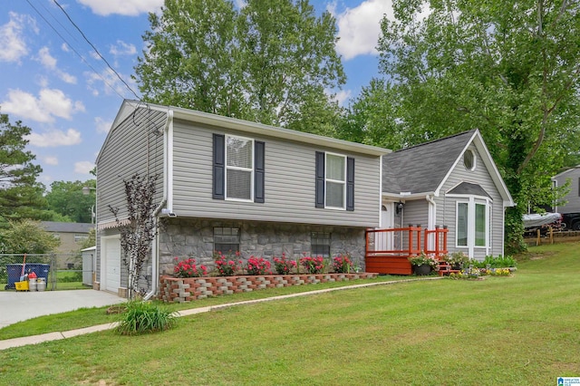 split level home with a front lawn, fence, stone siding, concrete driveway, and an attached garage