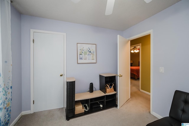 sitting room featuring baseboards, ceiling fan, and carpet