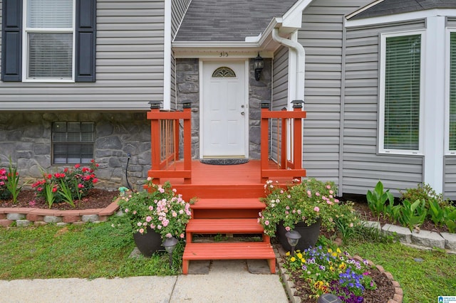 view of exterior entry with a shingled roof and stone siding
