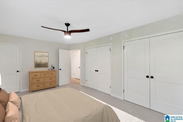 bedroom featuring baseboards, multiple closets, ceiling fan, and light carpet