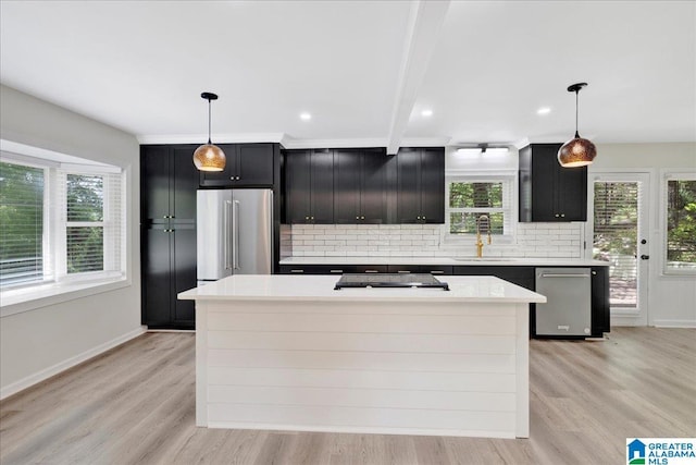 kitchen with a sink, dark cabinetry, stainless steel appliances, and tasteful backsplash