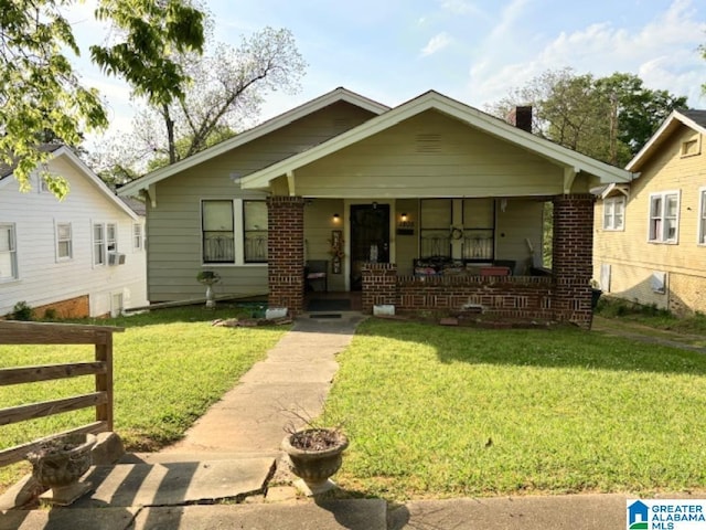 bungalow-style house featuring fence, a porch, brick siding, and a front yard