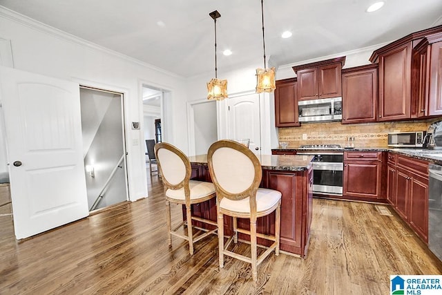 kitchen with a center island, appliances with stainless steel finishes, wood finished floors, and reddish brown cabinets