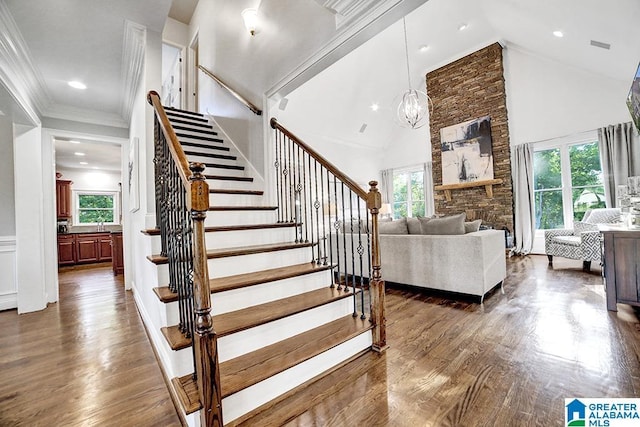 stairs featuring high vaulted ceiling, a wealth of natural light, and wood finished floors