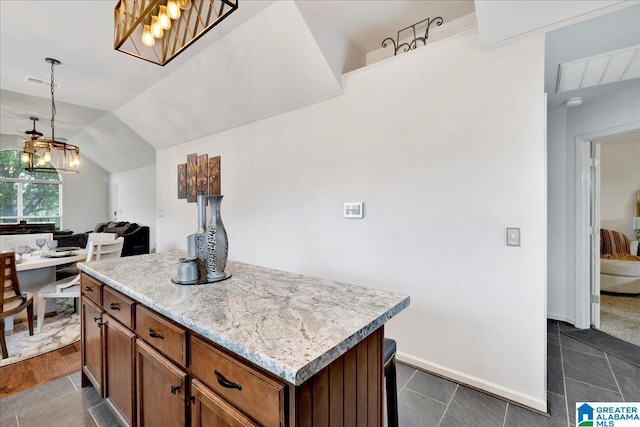 kitchen featuring visible vents, decorative light fixtures, a center island, vaulted ceiling, and open floor plan