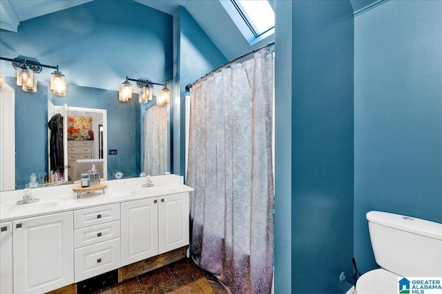 bathroom featuring a skylight, toilet, double vanity, and a sink