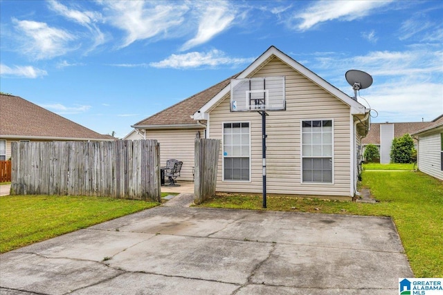 rear view of property featuring a patio area, fence, and a yard
