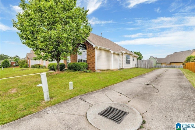 view of front of house featuring fence, concrete driveway, brick siding, and a front yard