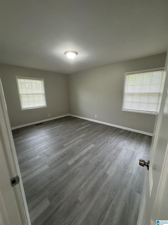 unfurnished room featuring baseboards and dark wood-style floors