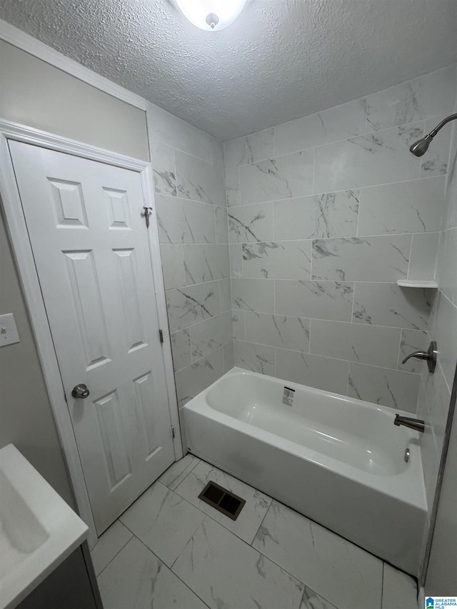 bathroom with shower / tub combination, a textured ceiling, and marble finish floor