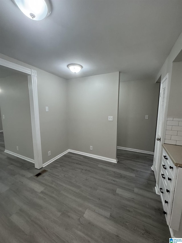 finished below grade area with dark wood-style flooring, baseboards, and visible vents
