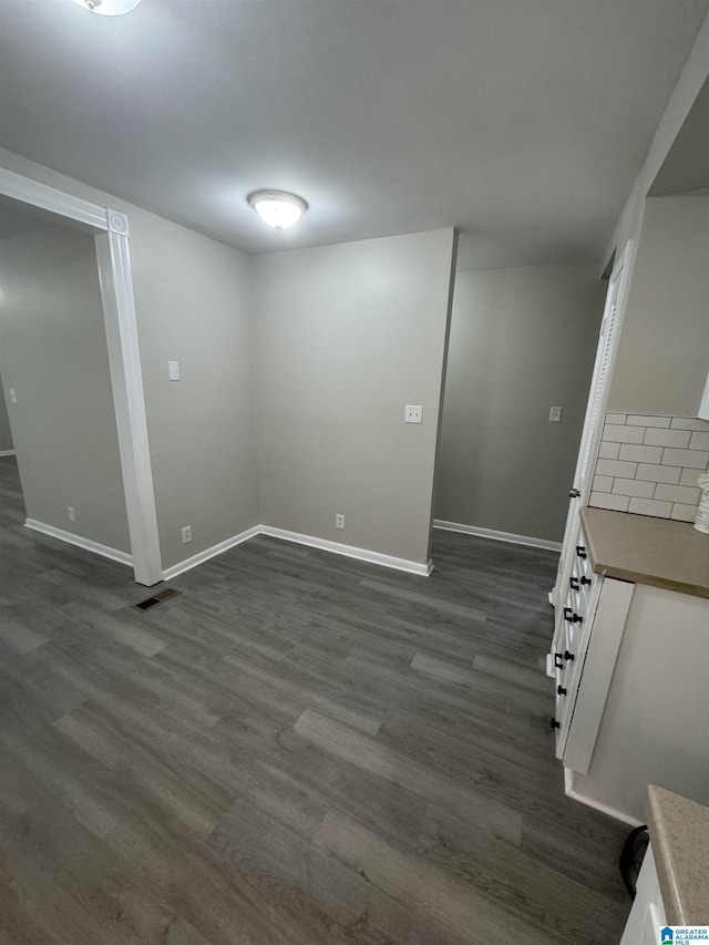 below grade area with dark wood-style flooring, baseboards, and visible vents