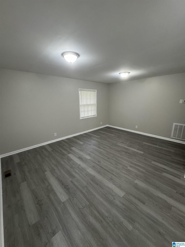 unfurnished room featuring baseboards, visible vents, and dark wood finished floors