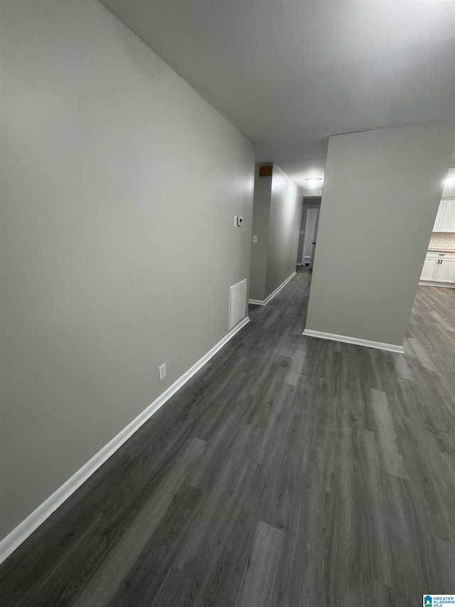 empty room featuring baseboards and dark wood-style flooring