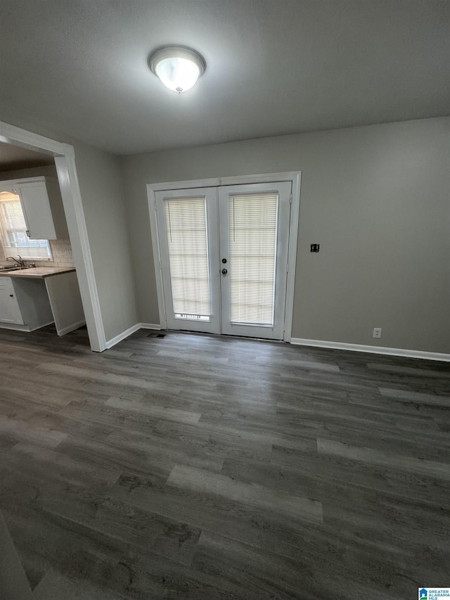 unfurnished dining area with a sink, baseboards, french doors, and dark wood-style flooring