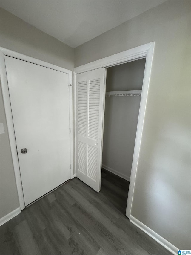 unfurnished bedroom featuring baseboards, wood finished floors, and a closet