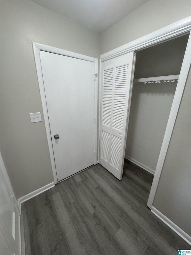 unfurnished bedroom with baseboards, wood finished floors, and a closet
