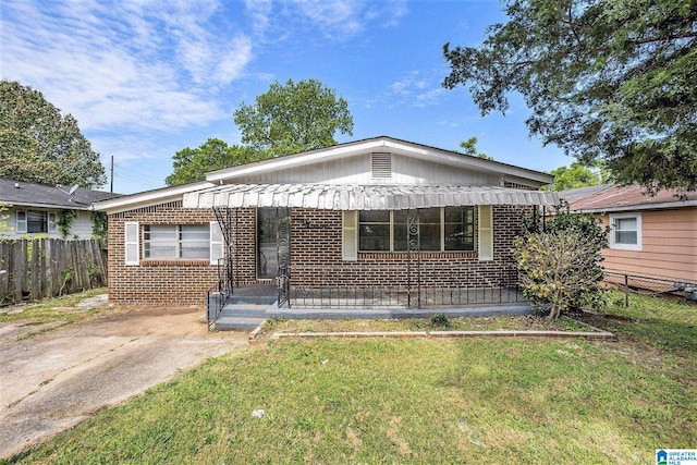 view of front facade with fence, covered porch, a front yard, and brick siding