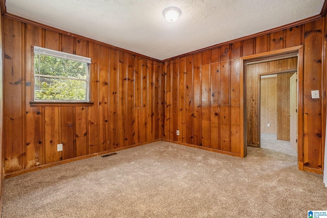 carpeted empty room featuring visible vents and wood walls