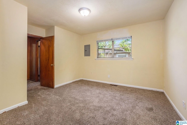carpeted empty room with baseboards, electric panel, and visible vents
