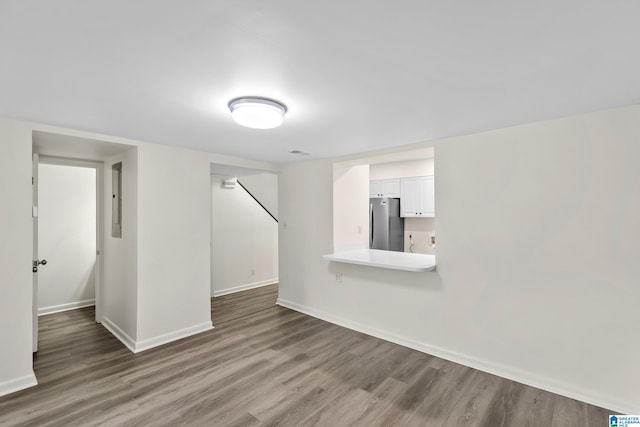 unfurnished living room featuring baseboards, wood finished floors, and visible vents
