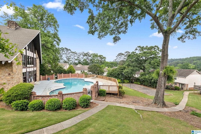 community pool featuring a lawn and fence
