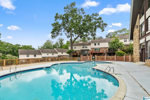 pool with fence, a patio, and a residential view