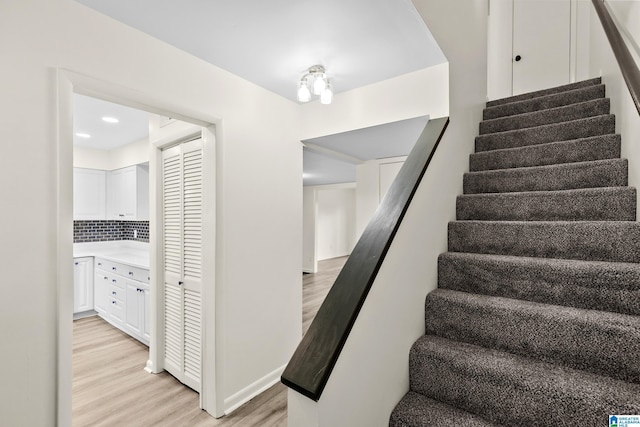 stairway with baseboards, recessed lighting, and wood finished floors