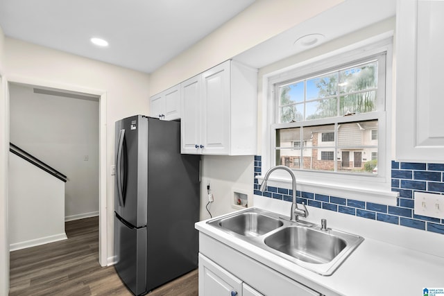 kitchen with freestanding refrigerator, a sink, white cabinets, and tasteful backsplash