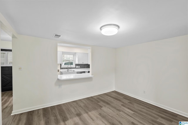 interior space with a sink, baseboards, wood finished floors, and visible vents