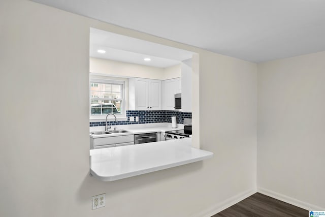 kitchen with dark wood-style flooring, appliances with stainless steel finishes, tasteful backsplash, a sink, and white cabinets